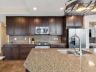 Experience modern living in this stunning kitchen featuring dark wood cabinetry and sleek granite countertops.
