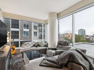 Experience modern urban living in this stylish apartment featuring a spacious living area with a large sectional sofa and a comfortable recliner.