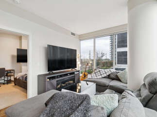 Experience modern urban living in this stylish condo featuring a spacious living area with a large flat-screen TV and a cozy electric fireplace.