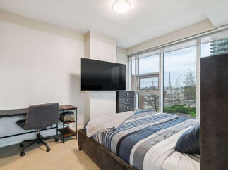 This modern bedroom features a comfortable bed with a stylish blue and grey striped comforter, perfect for a good night's sleep.