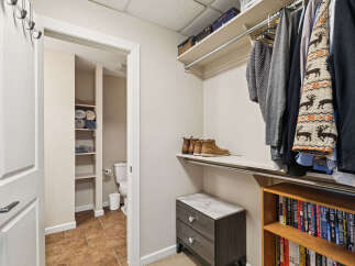 Discover organized living in this spacious walk-in closet, featuring ample shelving for folded towels and linens, a dedicated shoe shelf, and a hanging rod for your wardrobe.