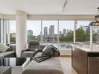 Experience breathtaking city views from this stunning condo, featuring a spacious sectional sofa and a comfortable recliner perfect for relaxation.