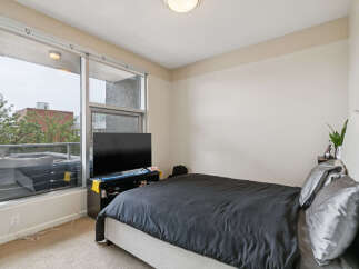 Experience modern urban living in this stylish bedroom featuring a comfortable bed with sleek grey bedding and a large flat-screen TV for entertainment.