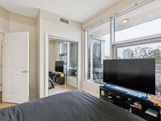 Experience modern living in this spacious bedroom featuring a large flat-screen TV and ample storage.