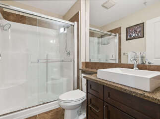 This modern bathroom features a sleek white vessel sink atop a dark wood vanity with granite countertops.