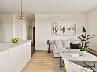 Experience modern living in this bright and airy apartment, featuring a sleek kitchen island with a contemporary faucet and a spacious living area perfect for relaxation.