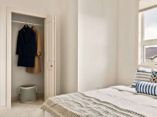 Discover this charming bedroom featuring a spacious closet with hanging coats and a decorative basket.