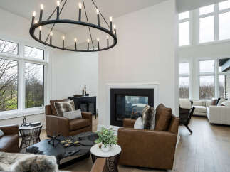Experience luxury living in this stunning modern home, featuring a grand living room with a soaring ceiling and a captivating circular chandelier.
