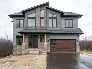 Discover modern luxury in this stunning two-story home, featuring a striking architectural design with a mix of grey siding and stone accents.