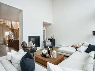 Experience modern luxury in this spacious living room, featuring a soaring ceiling and a sleek fireplace as the focal point.