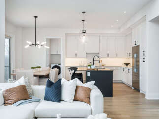Experience modern living in this open-concept space featuring a sleek white kitchen with a central island and a comfortable living area.