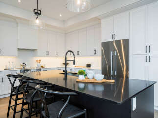 Experience modern luxury in this stunning kitchen, featuring sleek white cabinetry and a spacious dark stone island perfect for entertaining.