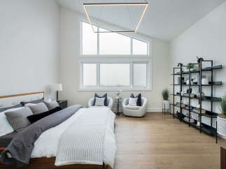 Experience modern luxury in this spacious bedroom featuring a vaulted ceiling and a striking geometric chandelier.