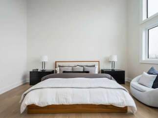 Experience modern comfort in this serene bedroom, featuring a plush king-size bed with a stylish wooden frame and a neutral color palette.