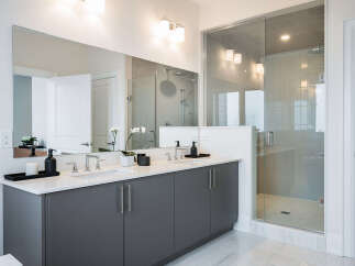 Experience modern luxury in this stunning bathroom featuring a spacious double vanity with sleek grey cabinetry and a pristine white countertop.