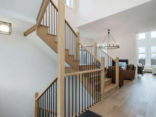 Experience modern luxury in this stunning home featuring a grand staircase with natural wood treads and sleek black balusters.