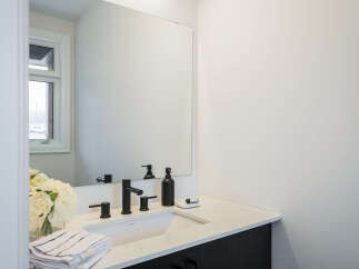 This modern bathroom features a sleek vanity with a quartz countertop and a minimalist black faucet.