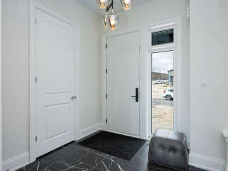 Step into this modern entryway featuring a sleek white door with horizontal paneling and a stylish black handle.