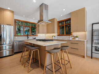 Experience modern luxury in this stunning kitchen, featuring sleek, light wood cabinetry and a spacious island with a built-in gas range.