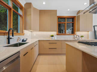 Experience modern luxury in this stunning kitchen, featuring sleek, light wood cabinetry and elegant marble countertops.