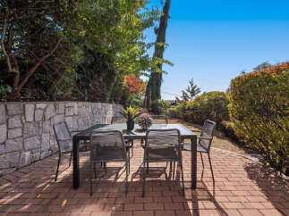 Enjoy outdoor dining and relaxation in this charming patio space, featuring a modern table and chairs set on a brick paver patio.
