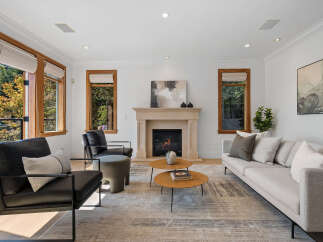 Experience modern living in this stunning living room, featuring a cozy fireplace and large windows that flood the space with natural light.