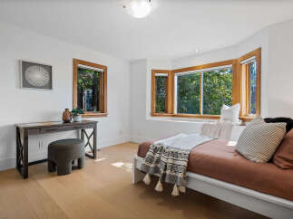 This bright bedroom features a comfortable bed with a stylish throw and decorative pillows, perfect for relaxation.
