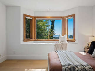 Experience breathtaking views from this charming bedroom, featuring a large bay window that floods the space with natural light.
