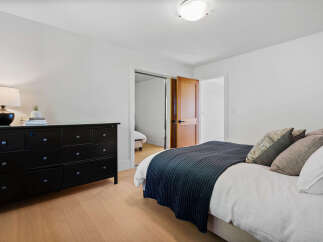 This inviting bedroom features a sleek black dresser with ample storage, complemented by a stylish table lamp.
