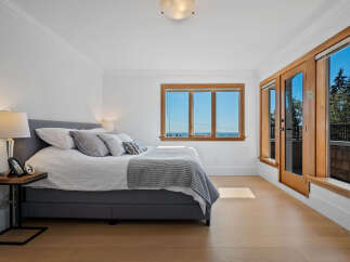 Experience breathtaking ocean views from this stunning bedroom, featuring a comfortable king-size bed and elegant grey bedding.