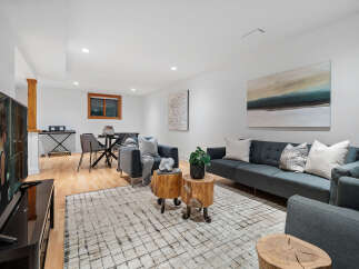 This modern living room features a spacious dark gray sectional sofa complemented by two accent chairs and unique tree stump side tables.