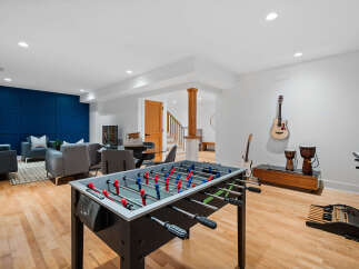This finished basement offers a perfect blend of entertainment and relaxation, featuring a vibrant blue accent wall and comfortable seating areas.