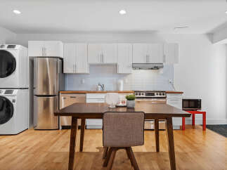 Discover this modern kitchen featuring sleek white cabinetry and stainless steel appliances, including a refrigerator and dishwasher.