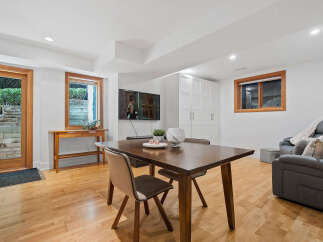 Discover comfortable living in this inviting space, featuring a modern dining area with a sleek wooden table and chairs, perfect for family meals.