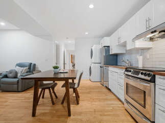 Discover this charming space featuring a modern kitchen with sleek white cabinetry, stainless steel appliances, and a convenient breakfast bar.