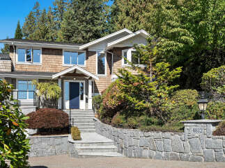 Discover this charming home featuring a welcoming blue front door and a picturesque stone pathway leading to the entrance.