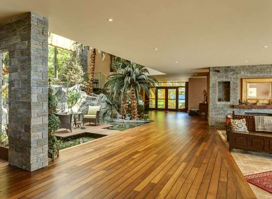 Experience luxury living in this stunning home featuring a unique indoor tropical oasis with a water feature and lush palm trees.
