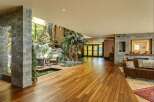 Experience luxury living in this stunning home featuring a unique indoor tropical oasis with a water feature and lush palm trees.