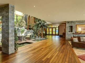 Experience luxury living in this stunning home featuring a unique indoor tropical oasis with a water feature and lush palm trees.
