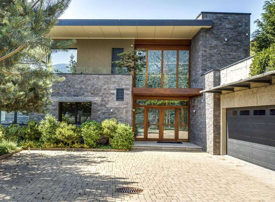 Experience modern luxury in this stunning home featuring a striking stone facade and expansive glass windows that invite natural light.