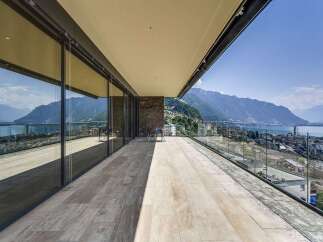 Experience breathtaking panoramic views from this expansive modern balcony, featuring floor-to-ceiling glass walls that seamlessly blend indoor and outdoor living.