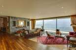 Experience breathtaking panoramic views of mountains and water from this stunning living room.