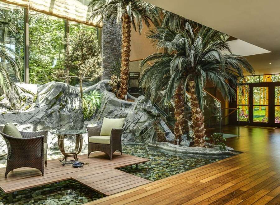 Experience luxurious indoor-outdoor living with this stunning atrium featuring a tranquil koi pond and lush tropical plants.