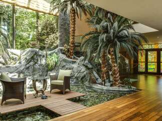 Experience luxurious indoor-outdoor living with this stunning atrium featuring a tranquil koi pond and lush tropical plants.
