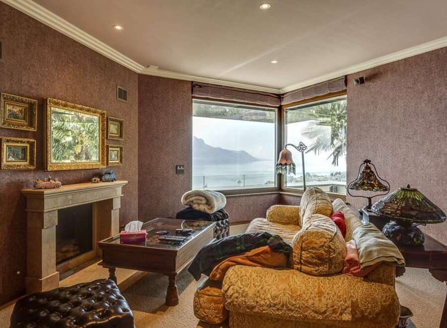 Experience breathtaking lake and mountain views from this elegant living room, featuring a cozy fireplace and plush seating.