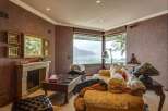 Experience breathtaking lake and mountain views from this elegant living room, featuring a cozy fireplace and plush seating.