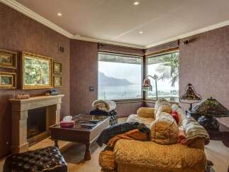 Experience breathtaking lake and mountain views from this elegant living room, featuring a cozy fireplace and plush seating.