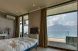 Experience breathtaking lake and mountain views from this luxurious bedroom, featuring a spacious bed and a private balcony perfect for enjoying the scenery.