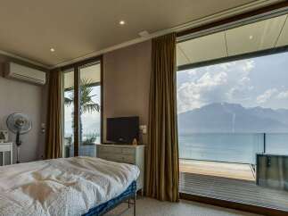 Experience breathtaking lake and mountain views from this luxurious bedroom, featuring a spacious bed and a private balcony perfect for enjoying the scenery.