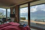 Experience breathtaking lake and mountain views from this luxurious bedroom, featuring expansive sliding glass doors that open onto a private deck.